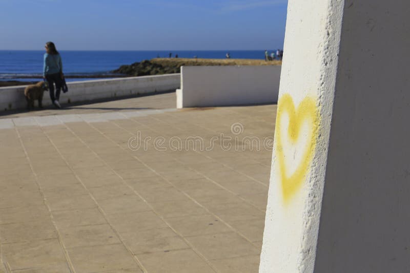 Yellow heart drawn on wall on Playa de la Costilla beach and promenade in Rota city, Cadiz, on a sunny day. Yellow heart drawn on wall on Playa de la Costilla beach and promenade in Rota city, Cadiz, on a sunny day