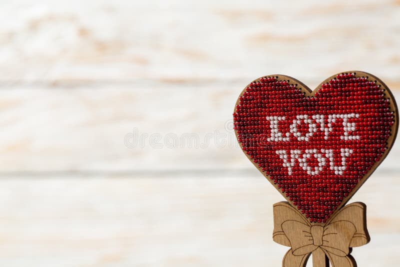 Coeur rouge brodé des perles sur un fond blanc en bois Le concept du jour du ` s de Valentine photo stock Coeur rouge brodé des perles sur un fond blanc en bois Le concept du jour du ` s de Valentine photo stock