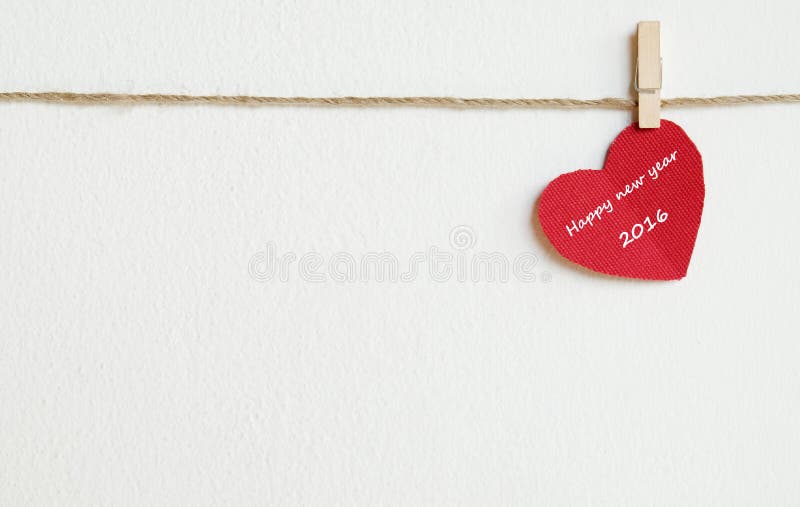 Coeur rouge de tissu avec le mot de la bonne année 2016 accrochant sur le Cl photo stock Coeur rouge de tissu avec le mot de la bonne année 2016 accrochant sur le Cl photo stock