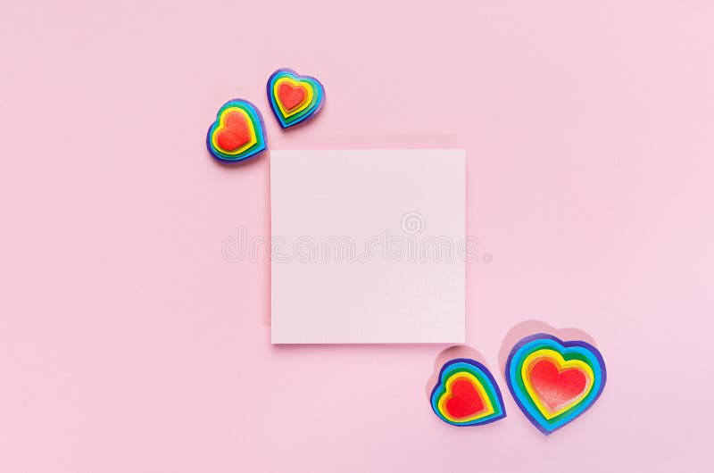 Coeurs multicolores lgbt de fond coloré de Saint Valentin avec le papier carré vide pour le texte sur la vue de dessus rose pastel photo libre de droits