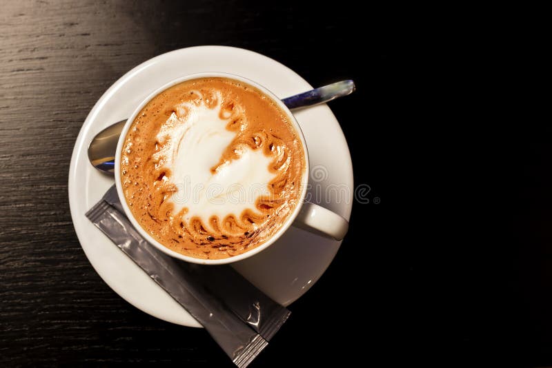 Cup of coffe on wood table. Heart shaped foam on top. Cup of coffe on wood table. Heart shaped foam on top.