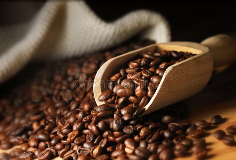 Primo piano dei chicchi di caffè con il misurino nell'illuminazione di umore.