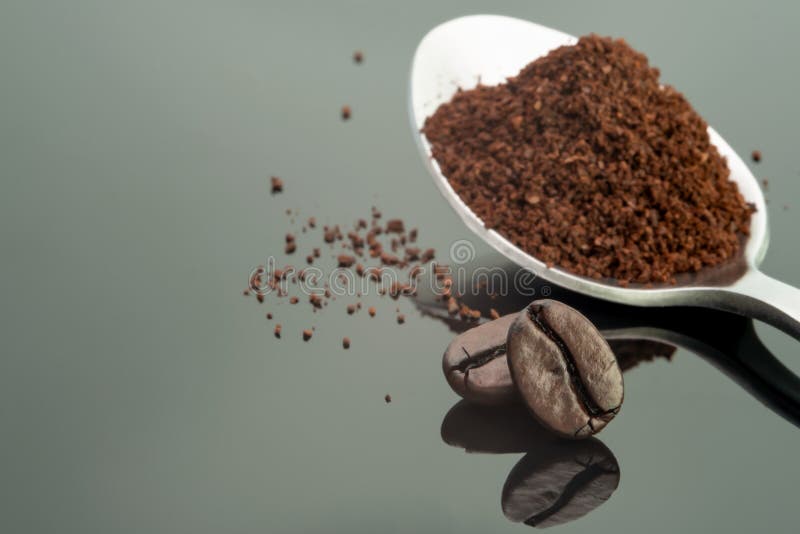 Coffee bean roast dark brown colour textured and ground coffee in spoon on shiny black backgrounds. Cutout picture pair harmony coffee bean roast dark brown stock photography Coffee bean roast dark brown colour textured and ground coffee in spoon on shiny black backgrounds. Cutout picture pair harmony coffee bean roast dark brown stock photography