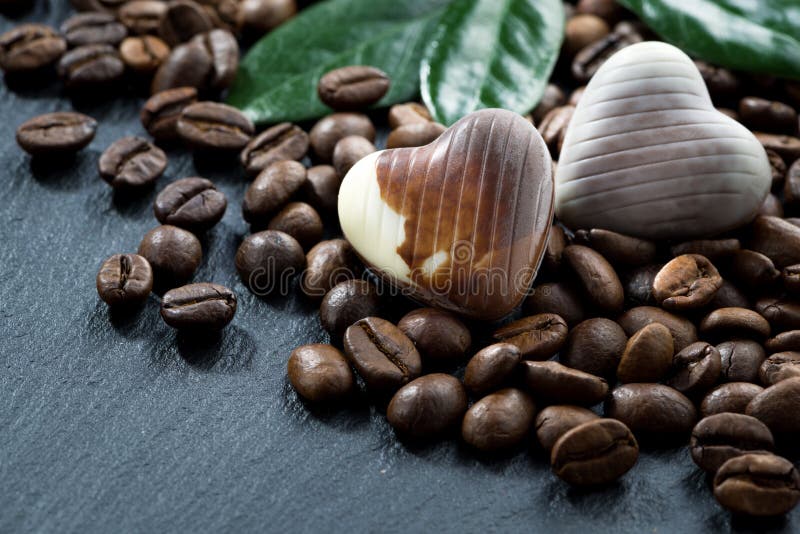Coffee beans and chocolate candies on a dark background, closeup