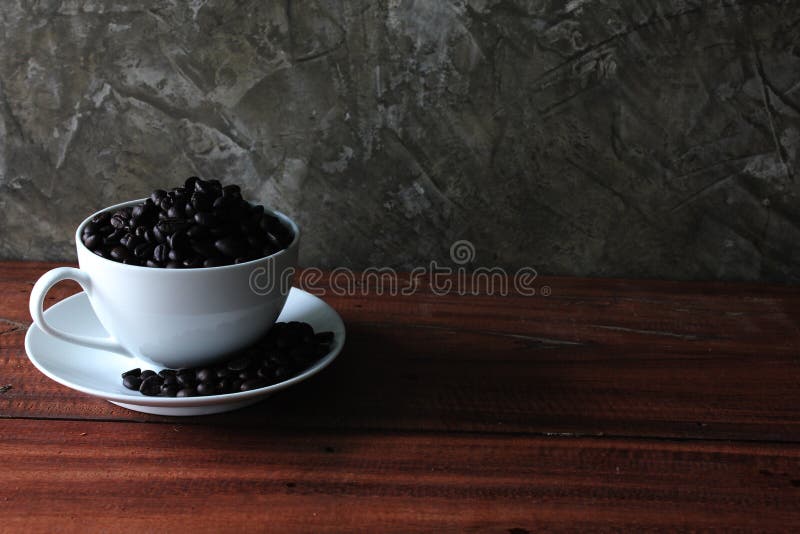 Coffee beans in a cup. Coffee beans in a cup on a wooden floor with free space and vintage old wall backgrounds textures stock image Coffee beans in a cup. Coffee beans in a cup on a wooden floor with free space and vintage old wall backgrounds textures stock image