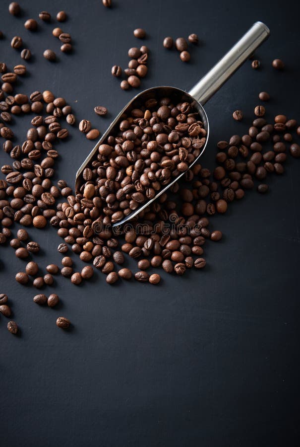 Coffee beans in a scoop on a black background