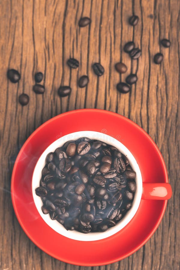 Coffee Beans with Smoke in Red Cup on Old Wooden Table with Copyspace