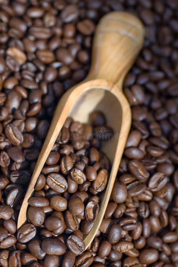 Coffee beans spilling out of wooden scoop