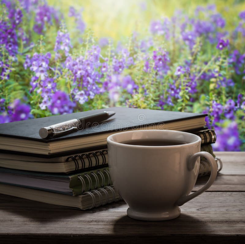 Coffee break with notebooks and pen on wooden table in the garden. Plank, notebook.