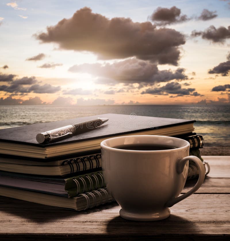 Coffee break with notebooks and pen on wooden table with view of