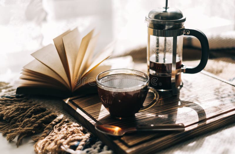 Coffee brewed in a French press and a cup on a board with book on a table stock images