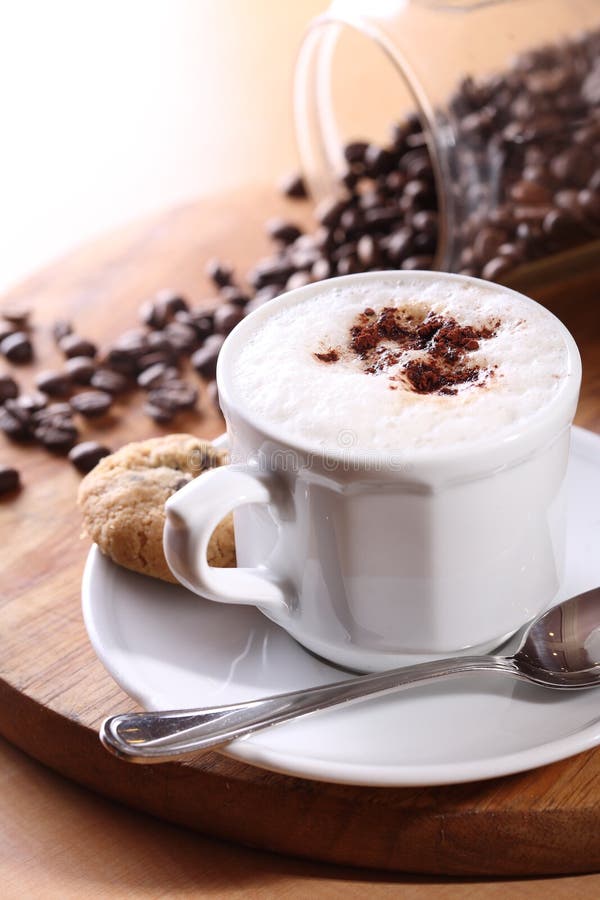 Una tazza di cappuccino con caffè in grani come sfondo.