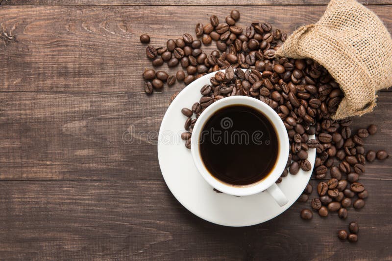 Coffee cup and coffee beans on wooden background. Top view.