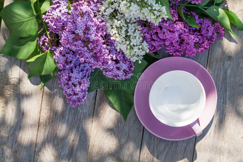 Coffee cup and colorful lilac flowers on garden table stock photos Coffee cup and colorful lilac flowers on garden table stock photos