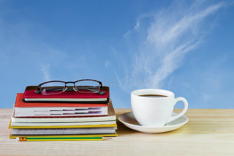 Coffee cup, glasses, and stack of book on wooden table with blur royalty free stock photo Coffee cup, glasses, and stack of book on wooden table with blur royalty free stock photo