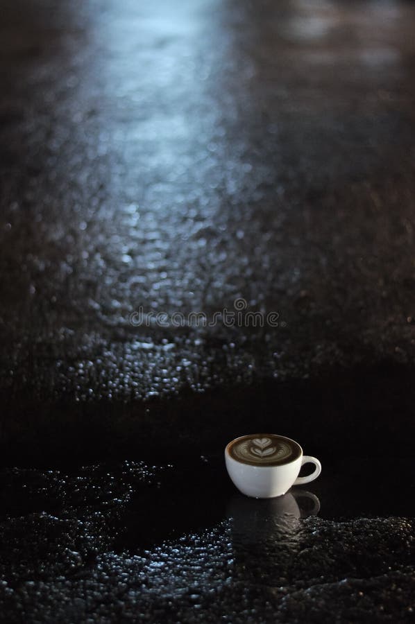 Coffee Cup with Latte Art on the Floor after Raining at Night Stock