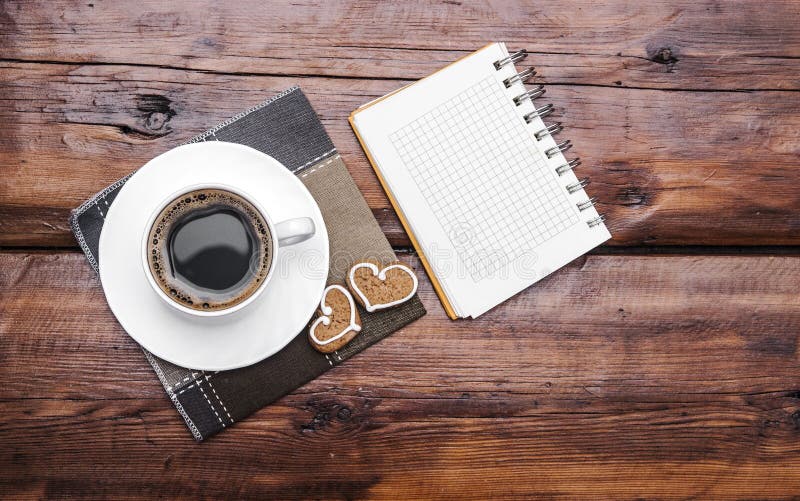 Coffee cup and note book on wooden tabletop