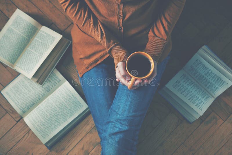 Ragazza avendo una pausa con una tazza di caffè dopo la lettura di libri o di studio.