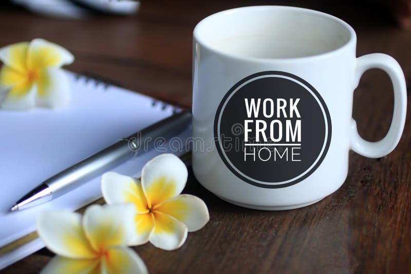 Coffee cup with text - work from home, with Bali frangipani flowers, pen and notebook on desk. Social distancing issues concept.
