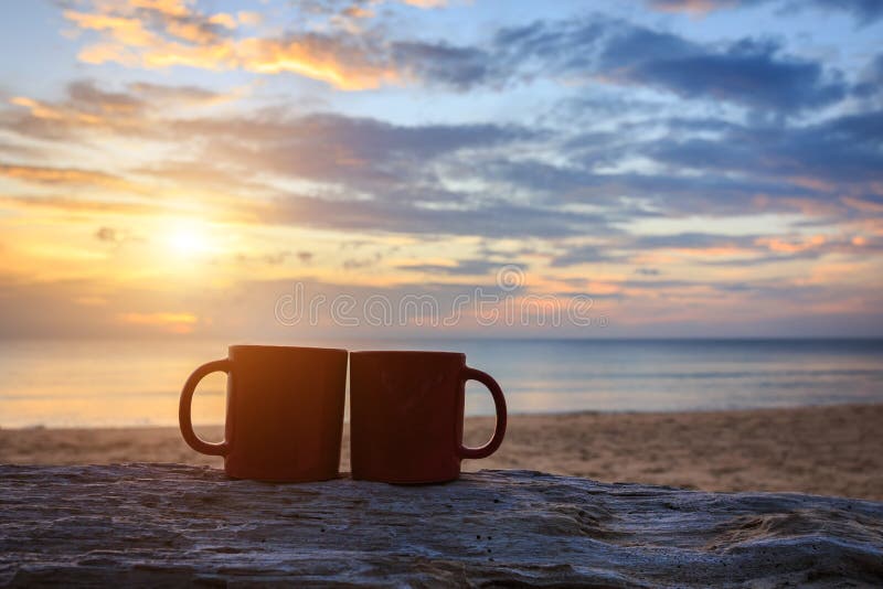 Coffee cup on wood log at sunset or sunrise beach