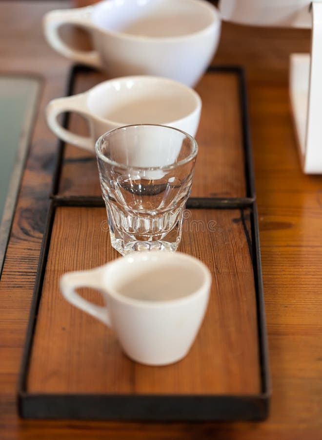 Coffee cups of various sizes next to tablet register in coffee shop on wooden background