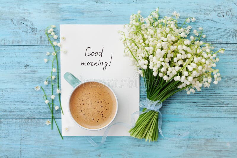 Coffee mug with bouquet of flowers lily of the valley and notes good morning on turquoise rustic table from above, beautiful breakfast, vintage card, top view, flat lay