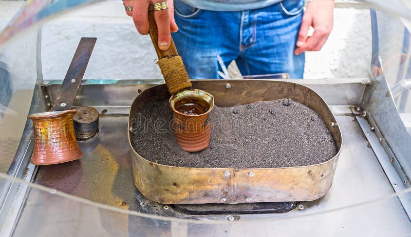 The traditional Turkish coffee is cooking in cezve on the hot sand in old town of Tbilisi, Georgia. The traditional Turkish coffee is cooking in cezve on the hot sand in old town of Tbilisi, Georgia.