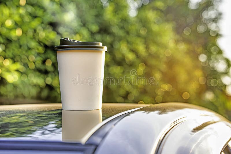 White paper coffee Cup with red lid on car roof. Paper Cup with hot tea on  the roof of the SUV close up on the background of the windshield Stock  Photo