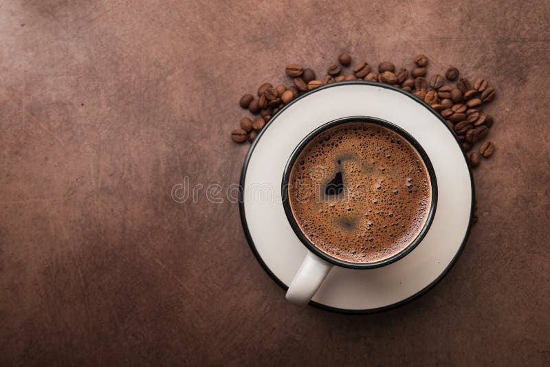 Coffee in a white cup with roasted beans