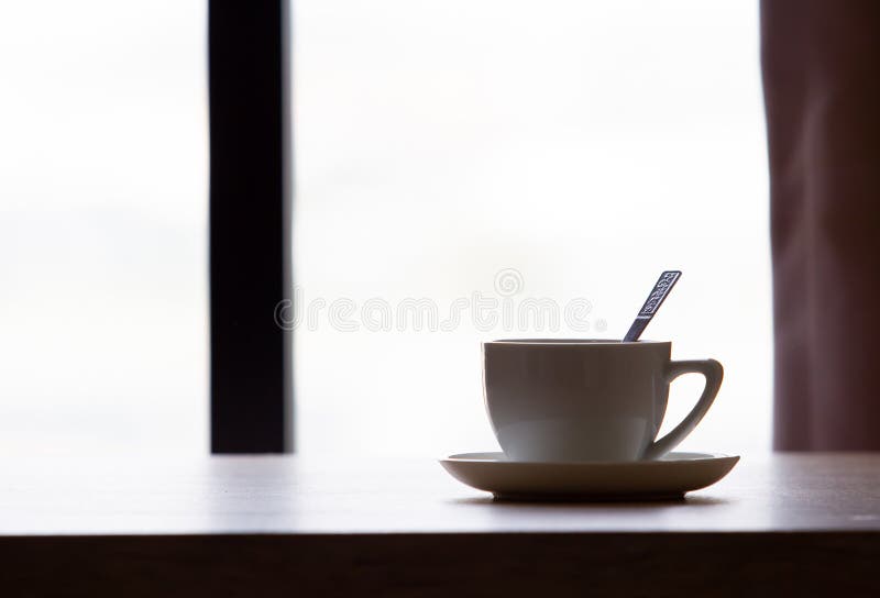 Coffee in White Cup on Wooden Table in Cafe with Lighting Background