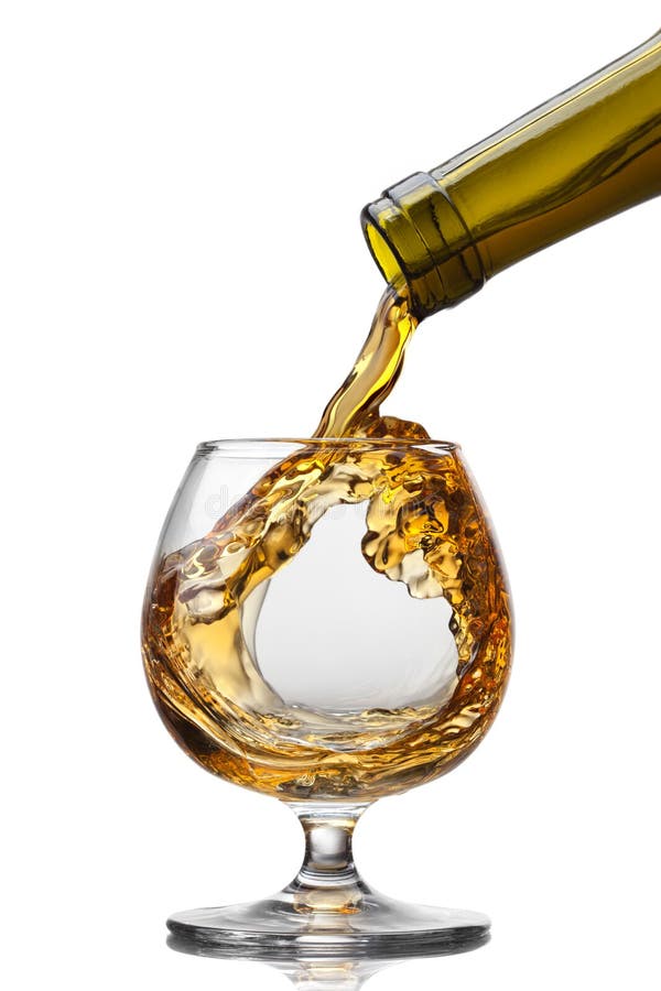 Cognac pouring from bottle into glass with splash on brown