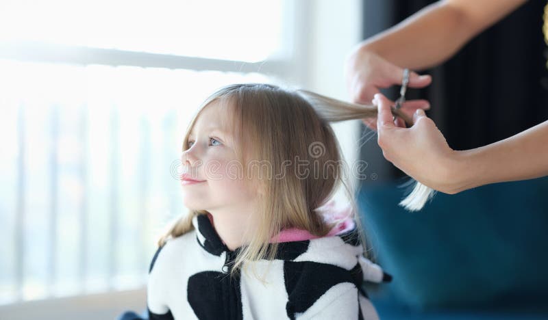 Coiffeur coupe cheveux petite fille dans salon de beauté image libre de droits