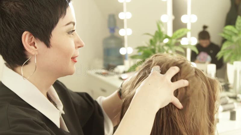 Coiffeur féminin faisant à massage la jeune femme principale dans le salon de coiffure Fermez-vous vers le haut du coiffeur pour banque de vidéos