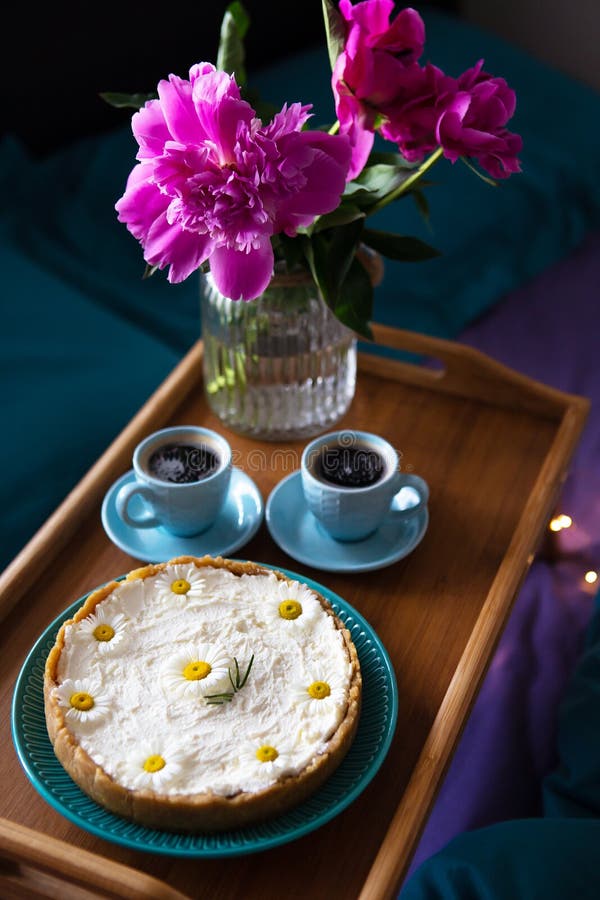 Colazione a letto Bellissime peonie, deliziose cheesecake e due tazze di caffè su un vassoio di legno immagini stock libere da diritti Colazione a letto Bellissime peonie, deliziose cheesecake e due tazze di caffè su un vassoio di legno immagini stock libere da diritti