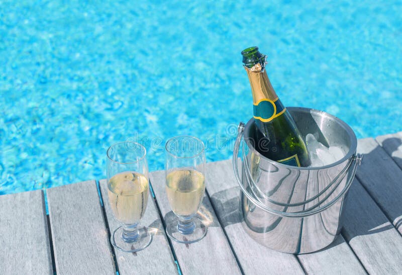 Cold champagne bottle in ice bucket and two glasses of champagne on the deck by the bottle in bucket and two glasses of champagne