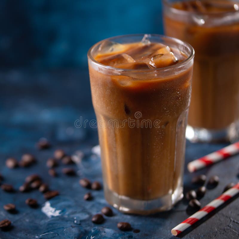 Cold Coffee with Ice Cubes and Milk on a Background with Coffee Grains
