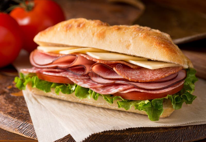 Un delizioso panino con affettati, foglie di lattuga, pomodoro e formaggio fresco ciabatta.