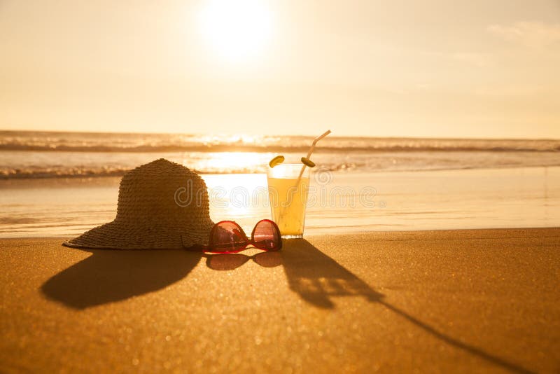 Cold drink with straw hat and sunglasses on the beach