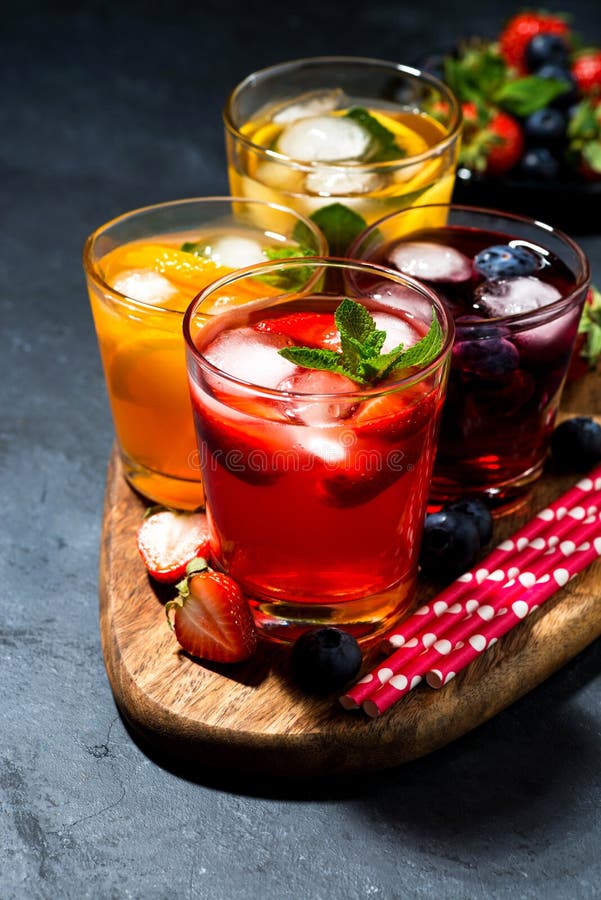 Cold fruit and berry beverages in assortment on dark background