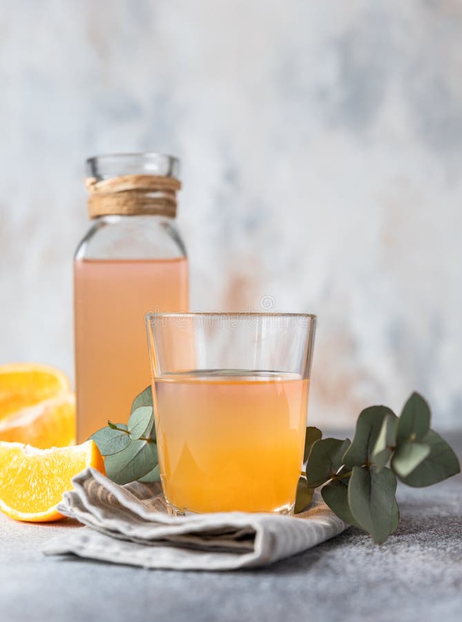 Cold and Refreshing Fresh Orange Juice in Glass and Bottle with Fresh Orange, Grey Background