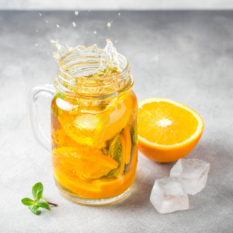 Cold tea with orange, mint and ice, sweet drink, refreshing lemonade, juicy cocktail. Spray, splash royalty free stock photography Cold tea with orange, mint and ice, sweet drink, refreshing lemonade, juicy cocktail. Spray, splash royalty free stock photography