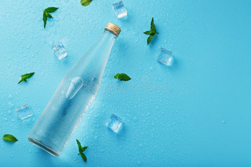 Cold Water Bottle, Ice Cubes, Drops and Mint Leaves on a Blue