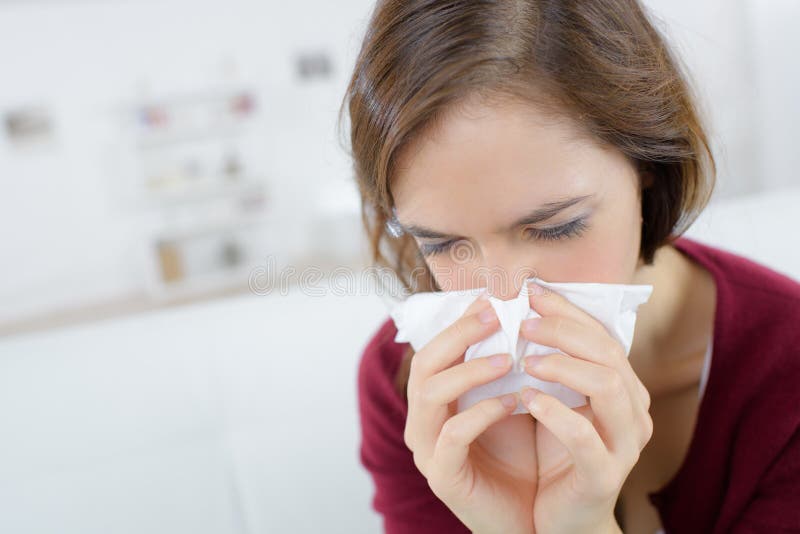 Cold woman holding handkerchieif blowing nose.
