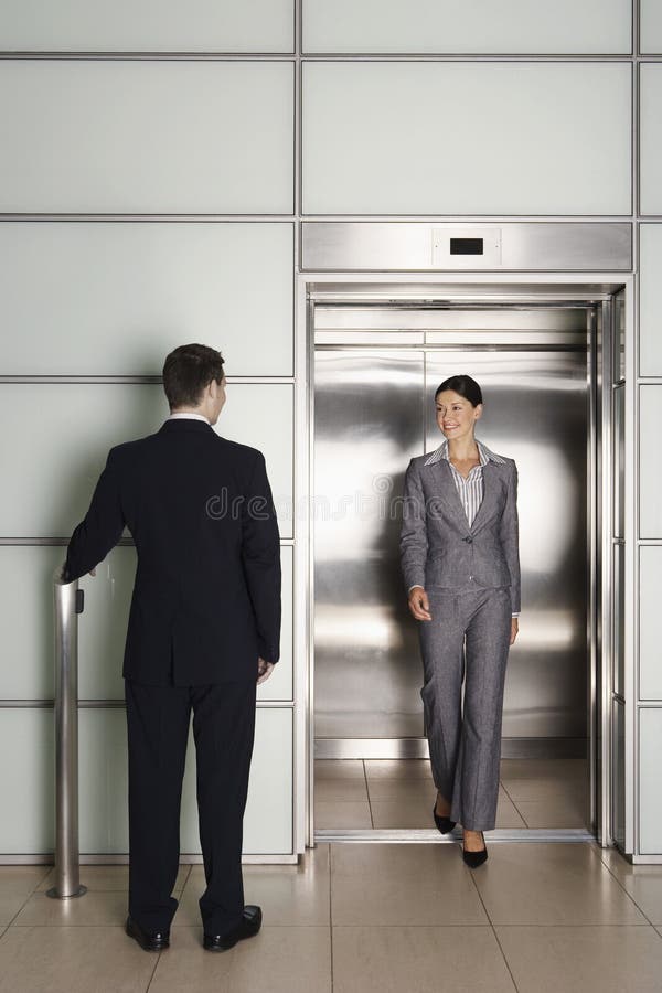 Colega de Looking At Female do homem de negócios que retira o elevador