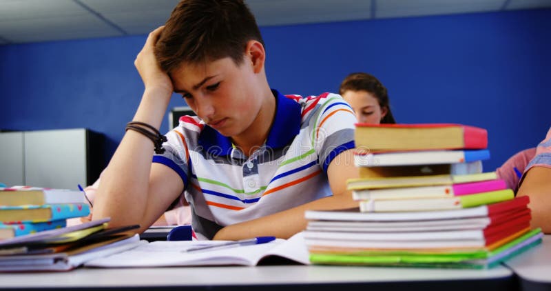 Colegial pensativo que se sienta en sala de clase