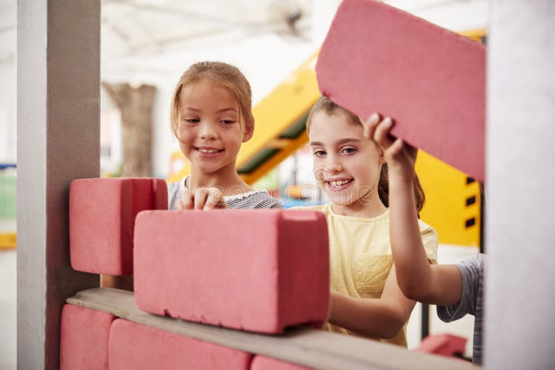 Colegialas que construyen con los ladrillos del juguete, cierre para arriba foto de archivo libre de regalías Colegialas que construyen con los ladrillos del juguete, cierre para arriba foto de archivo libre de regalías