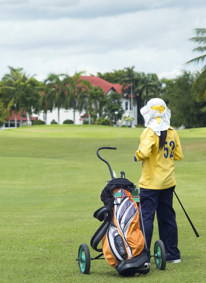 Golf caddie and bag on the fairway, admiring a luxury house on the outskirt of the golf course. The villa in the background out of focus. Golf caddie and bag on the fairway, admiring a luxury house on the outskirt of the golf course. The villa in the background out of focus.