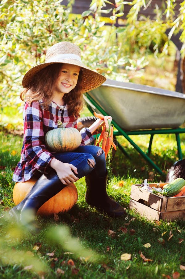 Colheita vegetal do outono feliz da colheita da menina da criança do fazendeiro no jardim foto de stock Colheita vegetal do outono feliz da colheita da menina da criança do fazendeiro no jardim foto de stock