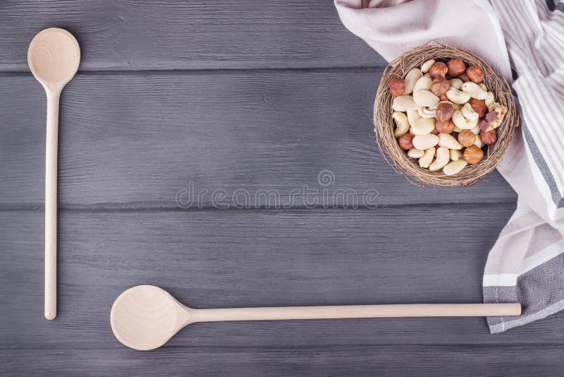 Colheres, toalha de cozinha e bacia de madeira com as porcas misturadas na madeira fotografia de stock Colheres, toalha de cozinha e bacia de madeira com as porcas misturadas na madeira fotografia de stock