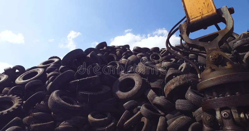 Colinas de neumáticos usados en instalaciones de reciclado en ángulo bajo de sol. almacen de video